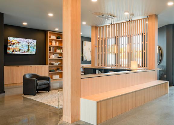 A lobby and seating area with a black chair and a wooden reception desk.