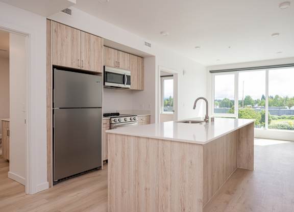 A kitchen with a refrigerator, microwave, and sink.