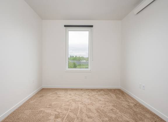 A room with a window and a view of trees outside.