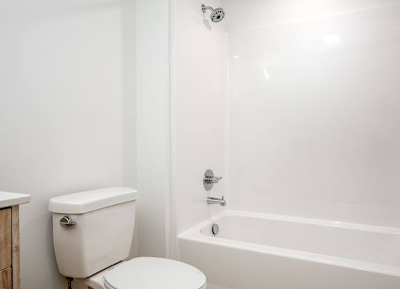 A white toilet sits next to a white bathtub in a bathroom.