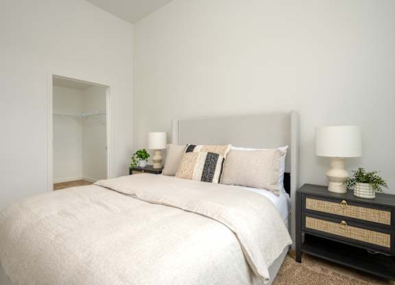 A bedroom with a large bed and two lamps on bedside tables.