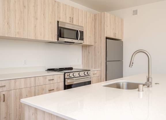 A kitchen with a white countertop and wooden cabinets.