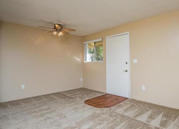 A room with a ceiling fan and a door leading to a balcony.
