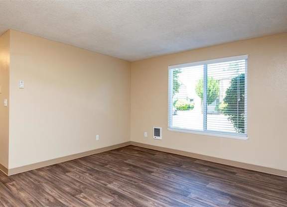 A room with wooden floors and a window with blinds.