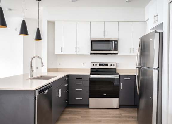 A modern kitchen with a refrigerator, oven, and microwave.
