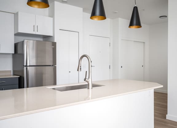 A modern kitchen with a stainless steel refrigerator and a white countertop.