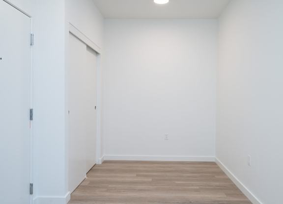 A room with a white door and wooden floor.