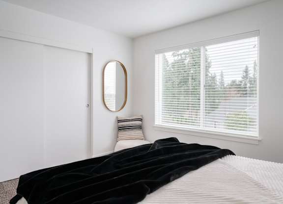 A bedroom with a large bed and a round mirror on the wall.