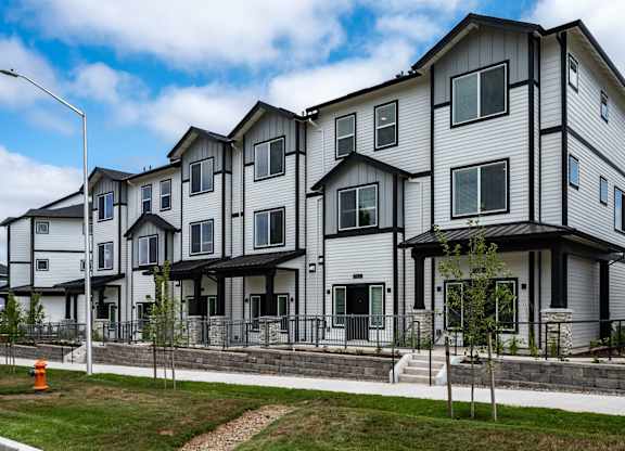 A row of modern townhouses with a sidewalk and a street lamp.