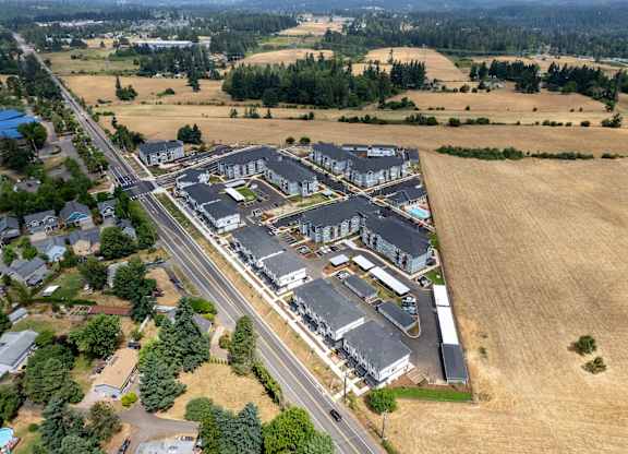 A large building complex is surrounded by a road and a field.