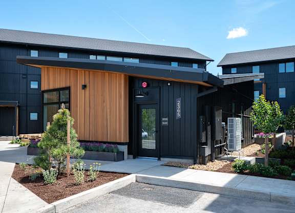 A modern building with a black exterior and a wooden entrance.