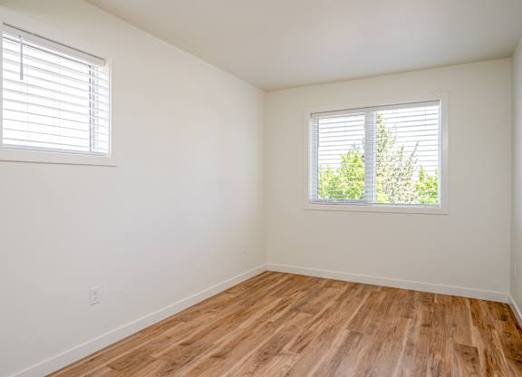 A room with wooden floors and two windows.