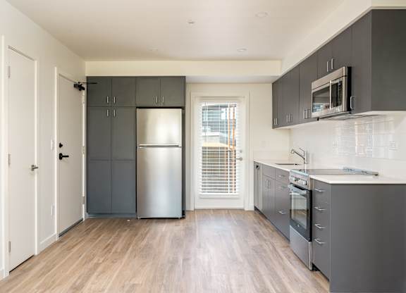A kitchen with a refrigerator, oven, and microwave.