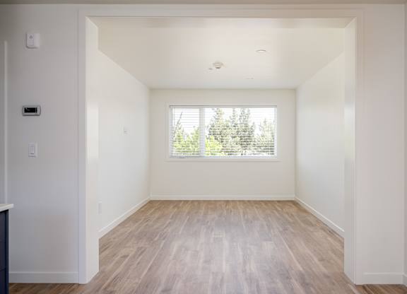 A room with a window and wooden flooring.