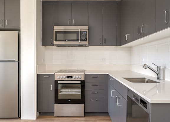 A modern kitchen with a stainless steel refrigerator and a built-in oven.