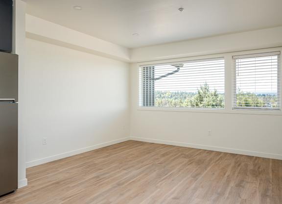A room with wooden flooring and a window with blinds.