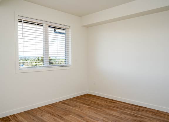 A room with a window and wooden flooring.