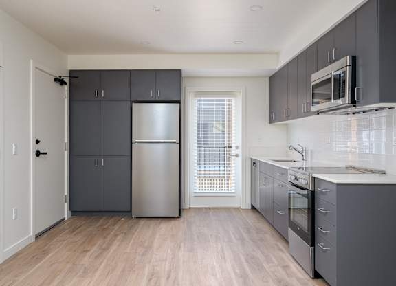 A kitchen with a refrigerator, oven, and microwave.