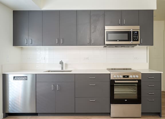 A modern kitchen with a stainless steel refrigerator, a double oven, and a microwave above the sink.