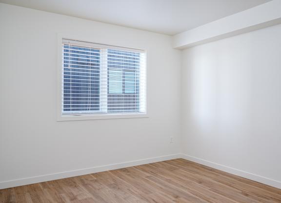 A room with a window and wooden flooring.