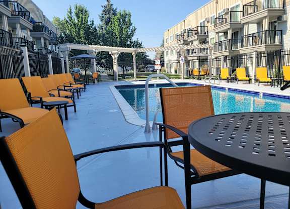 a poolSunset Apartments | Outdoor Seasonal Poolside patio with chairs and tables at an apartment building