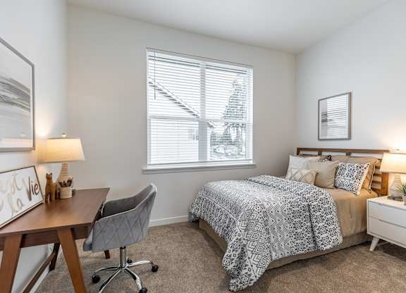 A bedroom with a bed, desk, and chair.