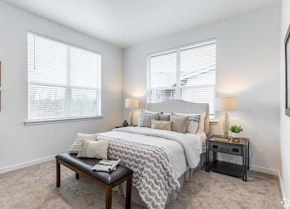 A bedroom with a large bed and a nightstand with a lamp.