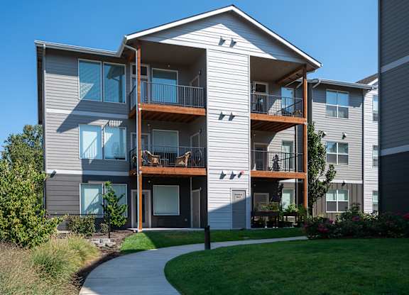 A modern two-story apartment building with a balcony and a small garden.