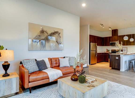 A living room with a couch, a coffee table, and a painting of horses on the wall.
