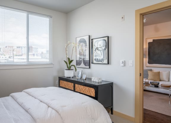 One Bedroom Apartments in Everett WA - The Waterline - Bedroom with Vinyl Hardwood Flooring, Area Rug, Stylish Decor, and Sliding Doors to the Balcony