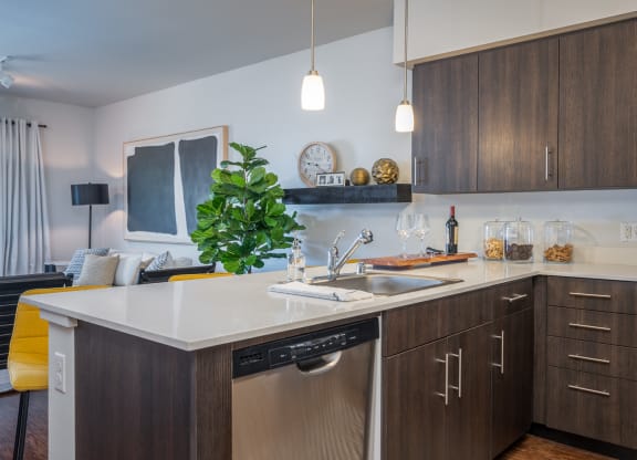 Dog-Friendly Apartments in Everett WA - The Waterline - Kitchen with Stainless Steel Appliances, Quartz Countertops, Dark Wood-Style Cabinetry, Pendant Lighting, Breakfast Bar, and Vinyl Hardwood Floo