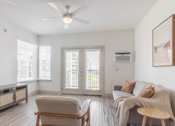 A living room with a grey couch, a wooden chair, and a ceiling fan.