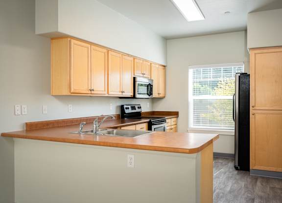 A kitchen with wooden cabinets and a black refrigerator.