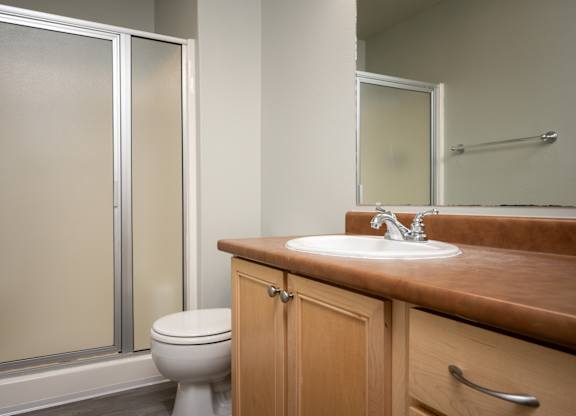 A bathroom with a toilet, sink, and mirror.