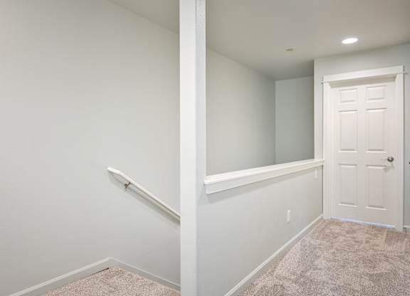 A white door is on the right side of a hallway.