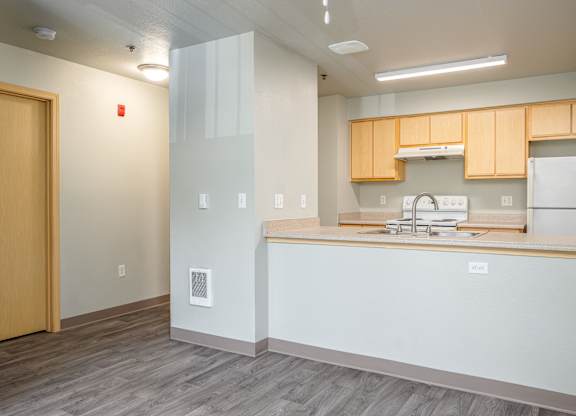 A kitchen with a sink, stove, and refrigerator.
