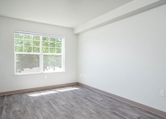 A room with a window and wooden flooring.