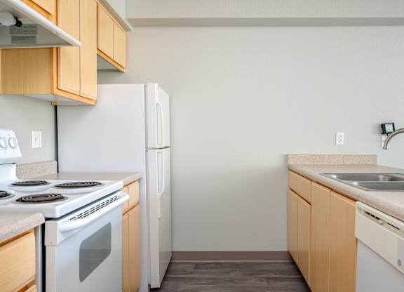 A kitchen with a white stove and white refrigerator with wooden cabinets.
