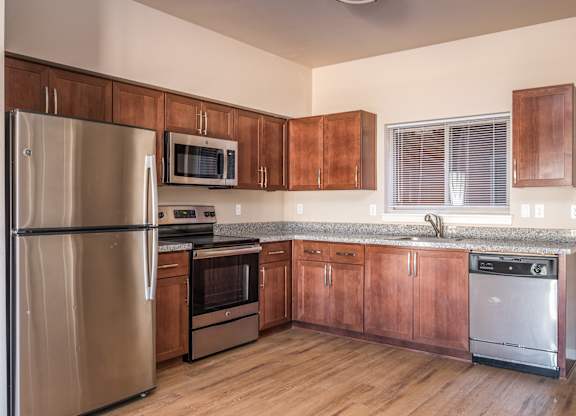 an empty kitchen with wooden cabinets and stainless steel appliances