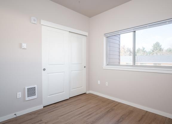 an empty bedroom with a window and a door