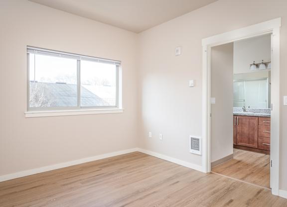 an empty bedroom with a large window and a bathroom