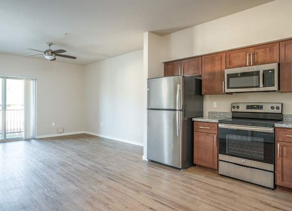 an empty kitchen with stainless steel appliances and wooden cabinets