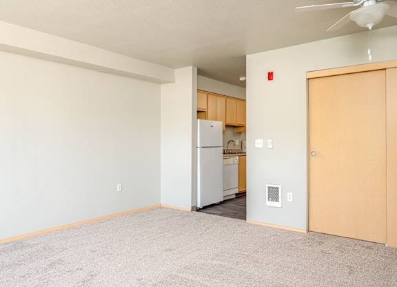 A room with a carpeted floor and a ceiling fan.