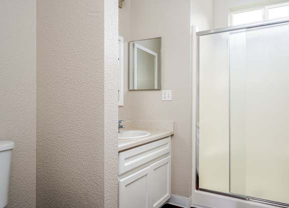 A bathroom with a sink, mirror, and shower.