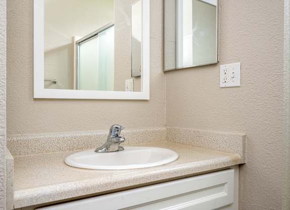 A white sink with a silver faucet is in a bathroom with a mirror above it.