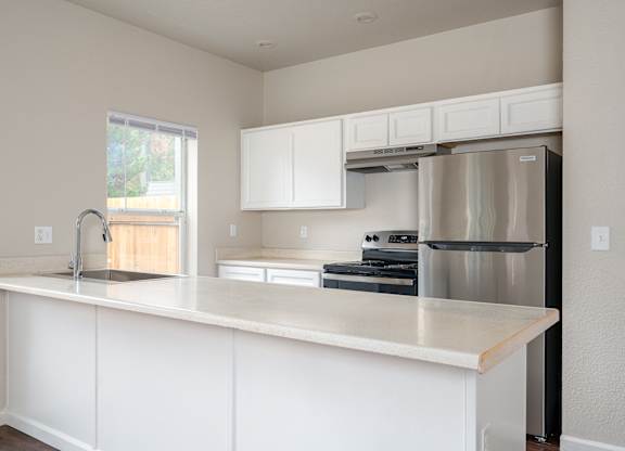 A kitchen with white cabinets and a stainless steel refrigerator.