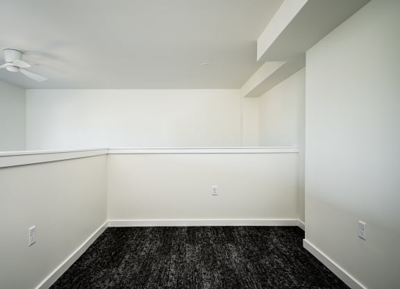 loft room with half wall, dark hardwood floor and white walls