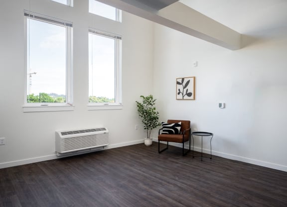 a living room with a chair, large windows and high ceilings
