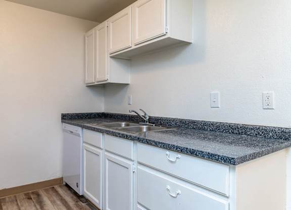 A kitchen with white cabinets and a granite countertop.