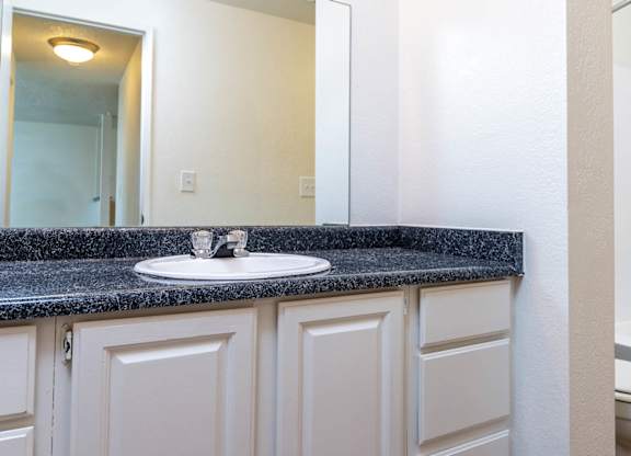 A bathroom with a sink, mirror, and toilet.